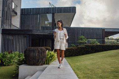 Konağın avlusunda telefonla yürüyen bir kadın.