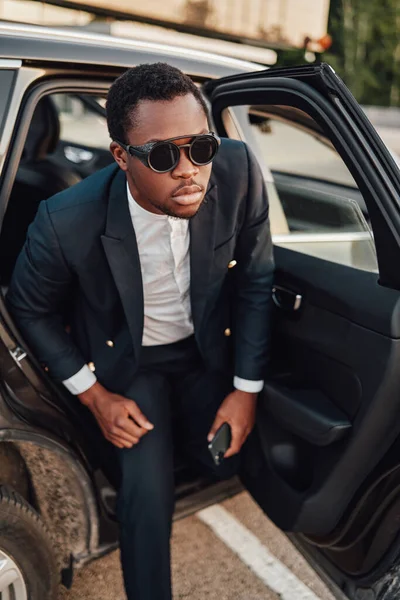 African businessperson with sunglasses getting out of car — Stock Photo, Image