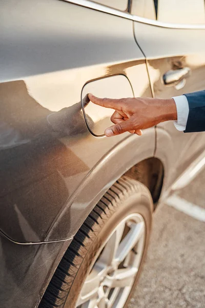 Shot of businessman with his finger on fuel tank of car — Stock Photo, Image