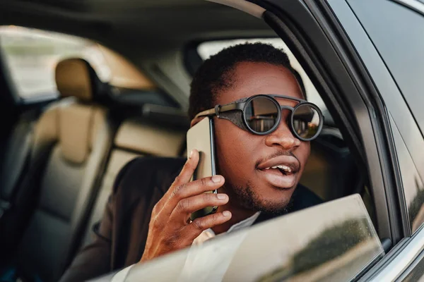 Successful african businessman with phone inside of car — Stock Photo, Image