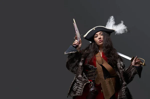 Modelo femenina vestida de pirata con sable y pistola — Foto de Stock