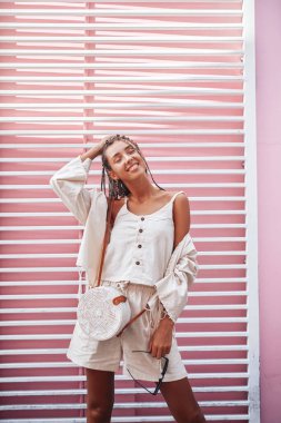 Pembe duvarlara karşı poz veren neşeli kadın.