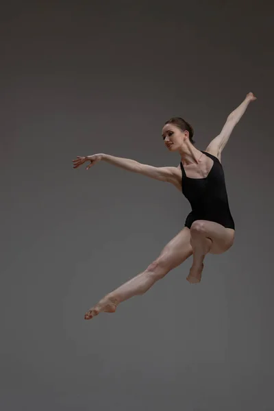 Професійний стрибок балерини танцює на сірому фоні — стокове фото