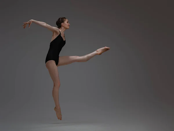 Bailarina profesional saltando bailando sobre fondo gris — Foto de Stock