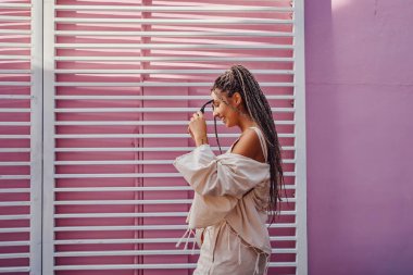 Pembe duvarlara karşı poz veren neşeli kadın.