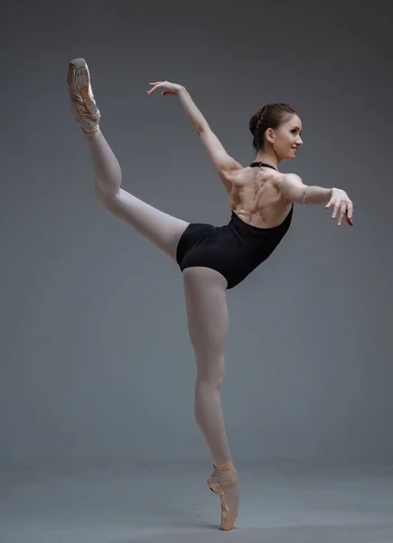 Elegante bailarina que se queda en una pierna dentro del estudio — Foto de Stock