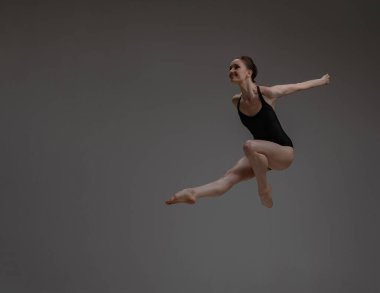 Gri arka planda dans eden profesyonel balerin.