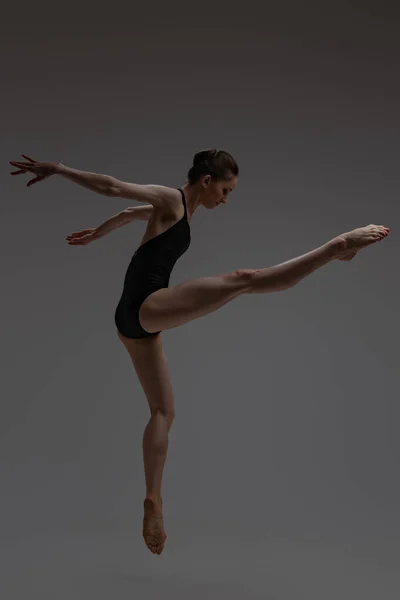Vista lateral de la bailarina saltando sobre fondo gris — Foto de Stock