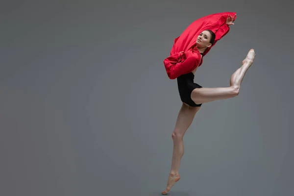 Jumping ballerina in tutu holding red silk — Stock Photo, Image