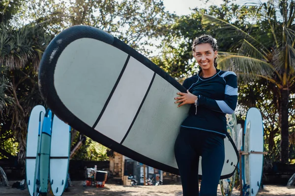 Smiling woman in wetsuit with board on beach — Stock Photo, Image