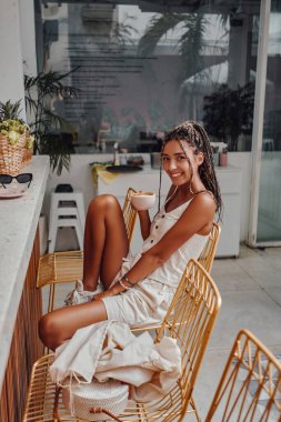 Kafede oturan ve kahve içen rastalı kadın.