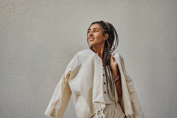 Glimlachende vrouw in trendy kleding poseren tegen de muur — Stockfoto