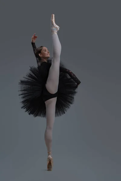 Bailarina ágil em vestido preto contra fundo cinza — Fotografia de Stock