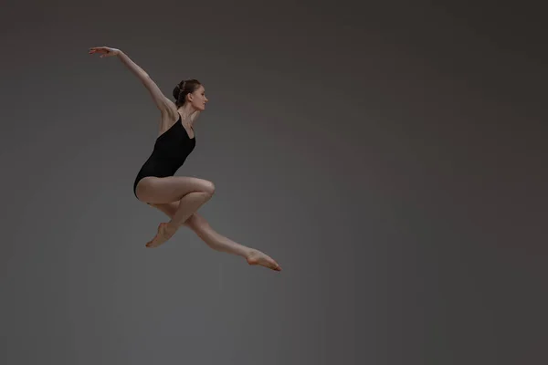 Професійний стрибок балерини танцює на сірому фоні — стокове фото