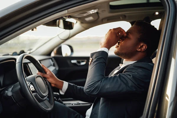 Exhausted african businessperson sitting inside of car holding wheel. — Stock Photo, Image