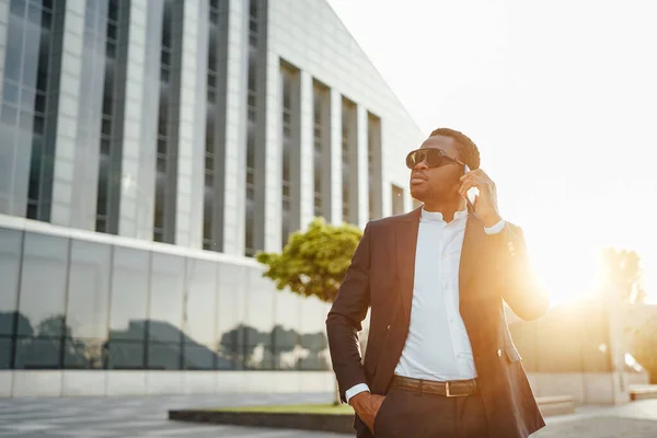 Hombre de negocios africano hablando por teléfono contra paisaje urbano —  Fotos de Stock