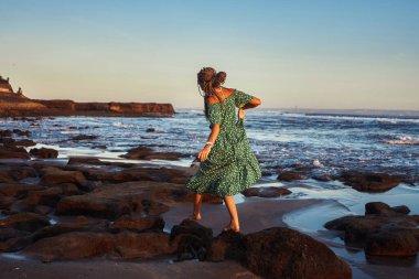 Gün batımında Bali 'de sahilde yürüyen bir kadın