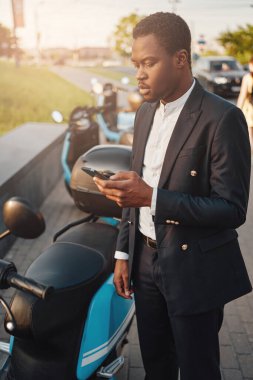 Dışarıda telefonu ve bisikleti olan ciddi bir Afrikalı iş adamı.