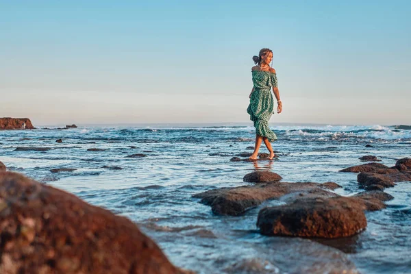 На заході сонця жінка йде на пляжі. — стокове фото