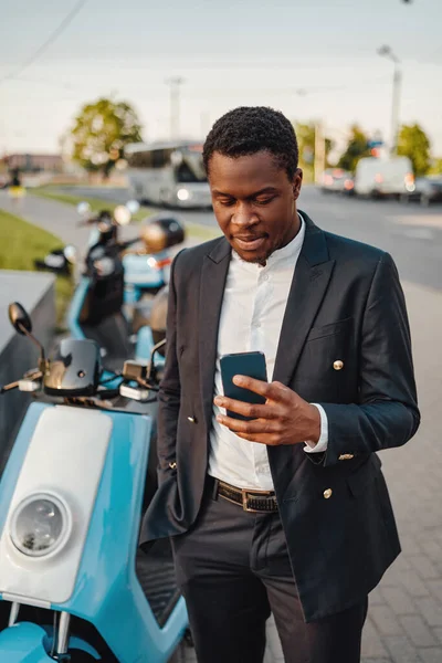 Grave uomo d'affari africano con telefono e bici all'aperto — Foto Stock