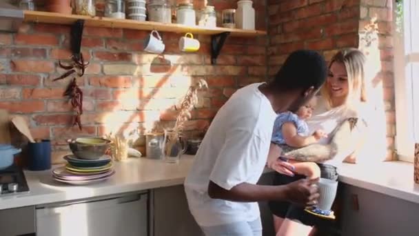 Svart man och vit kvinna leker med sin afrikanska dotter i köket. — Stockvideo