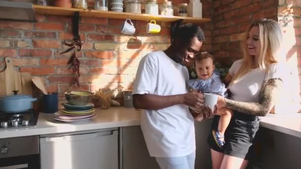Authentic shot of mixed race family playing and laughing at kitchen in sunlight. — Video