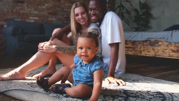 Mixed ethnicity parents relaxing while cute kid daughter playing on carpet. — Video