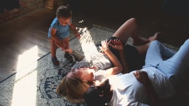 Young mixed race couple is lying on beautiful new carpet on living room. — Stock videók