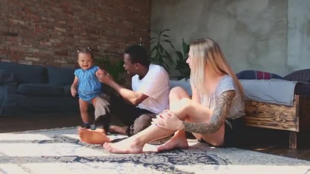 Close up of mixed race parents encouraging baby daughter to take first steps. — Video