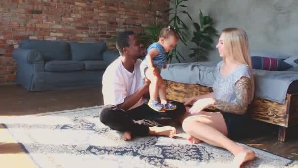 Slow motion active young mixed race couple parents sitting on floor and playing. — Stok video