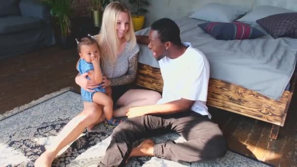 Wide shot of mixed race baby, caucasian mother, african dad sitting in room. — Stock videók