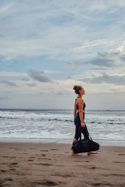 Seitenansicht einer Frau, die am Strand gegen das Meer läuft — Stockfoto