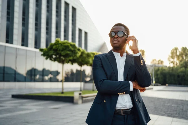 Hombre de negocios africano hablando por teléfono contra paisaje urbano —  Fotos de Stock