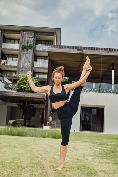 Flexible Frau streckt erhobenes Bein gegen Villa — Stockfoto