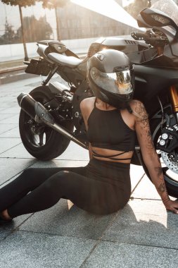Kasklı ve motosikletli bir kadının görüntüsü.