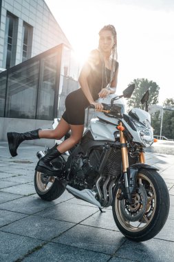 Şehirde motorsiklet süren genç bir kadın.