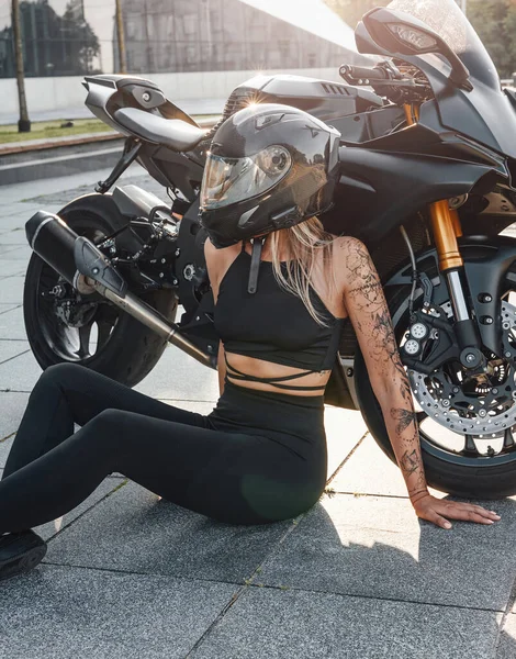 Спортивная женщина позирует со своим современным чёрным мотоциклом — стоковое фото
