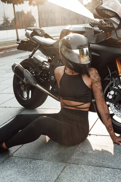 Снимок женщины со шлемом и мотоциклом, смотрящей в сторону — стоковое фото