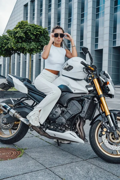 Модная женщина-байкер сидит на современном мотоцикле в городе — стоковое фото
