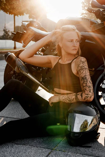 Kvinna poserar med motorcykel i ljuset av solen — Stockfoto