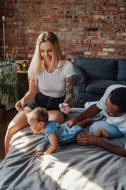 Neşeli melez çift ve kızları yatak odasında.