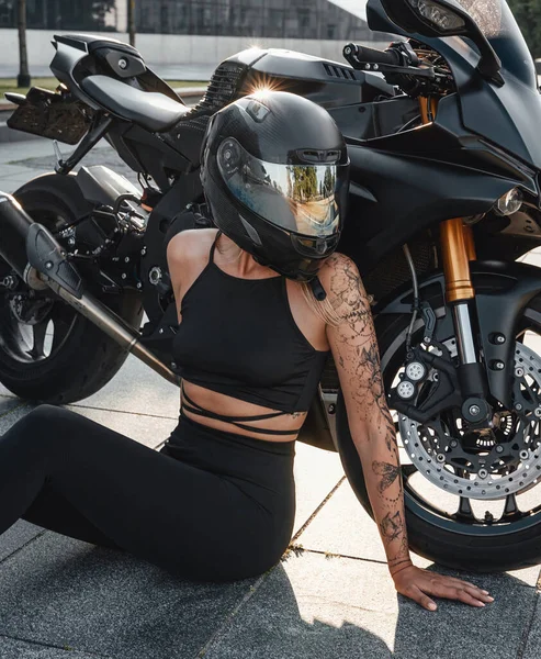 Снимок женщины со шлемом и мотоциклом, смотрящей в сторону — стоковое фото