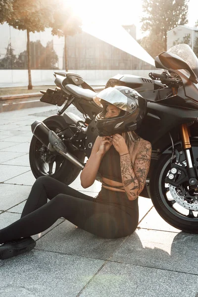 Γυναίκα ποδηλάτης απογειώνεται κράνος μοτοσικλέτας κάθεται στην άσφαλτο — Φωτογραφία Αρχείου
