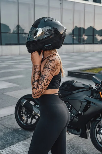 Woman taking off motorcycle helmet outside on city street — Stockfoto