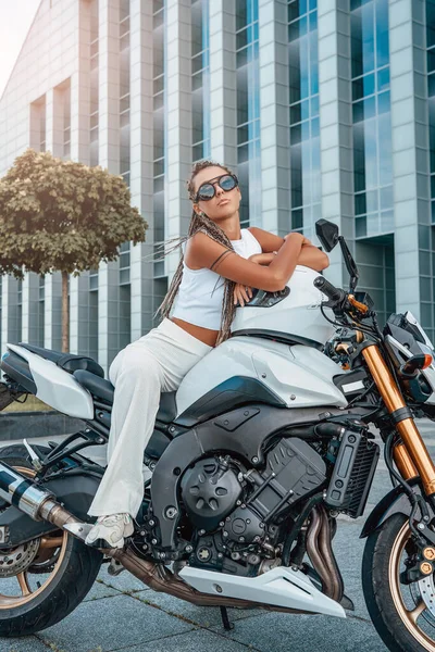 Женщина в стильной одежде сидит на мотоцикле — стоковое фото