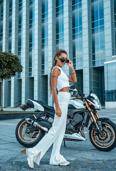Tiro de mulher elegante posando contra moto e construção — Fotografia de Stock