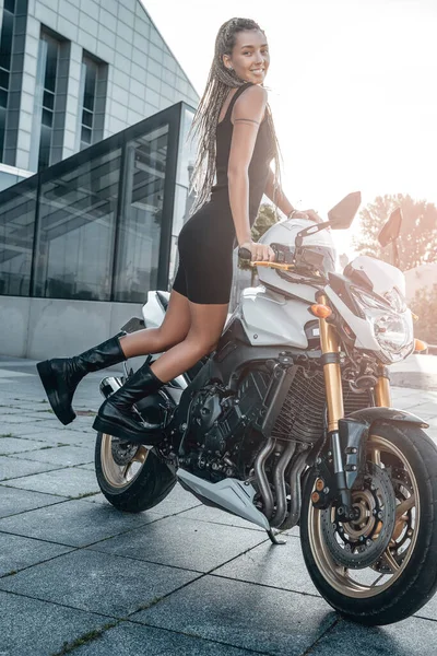 Радостная женщина-байкер на мотоцикле на улице в городе — стоковое фото