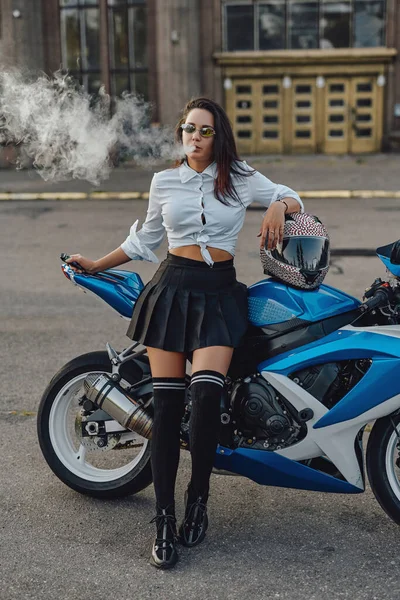 Glamour woman biker smoking cigarette leaning bike outside — Stock Photo, Image