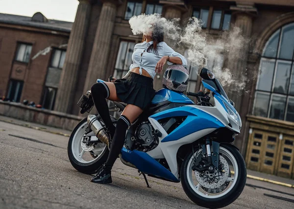 Модная женщина в солнцезащитных очках и вапе позирует на мотоцикле — стоковое фото