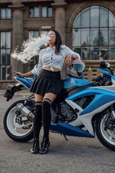 Жінка одягнена як школярка позує з мотоциклом зовні — стокове фото
